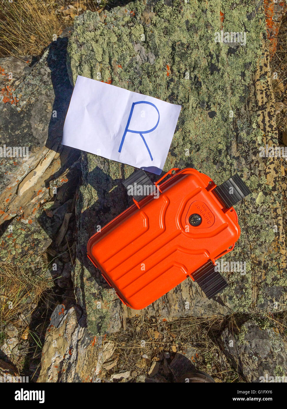 Orange geo cache con un pezzo di carta con un r Foto Stock