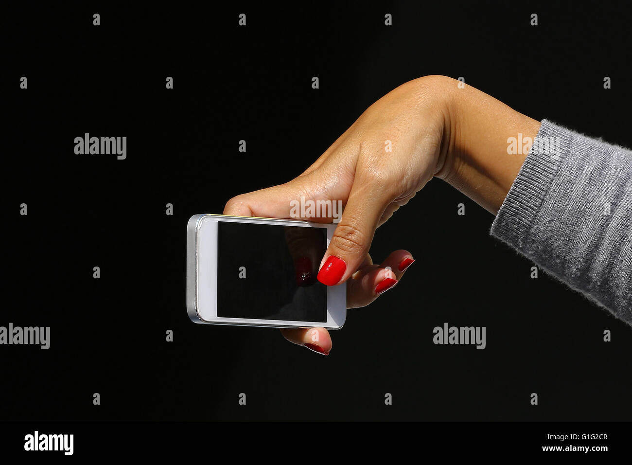 Donna di mano con le unghie rosse in possesso di un telefono cellulare di scattare una foto isolato su nero Foto Stock