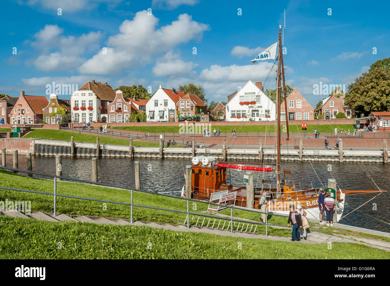 Facciate di case storiche su Sielstrasse e barca nel porto di Greetsiel, Bassa Sassonia, Germania Foto Stock