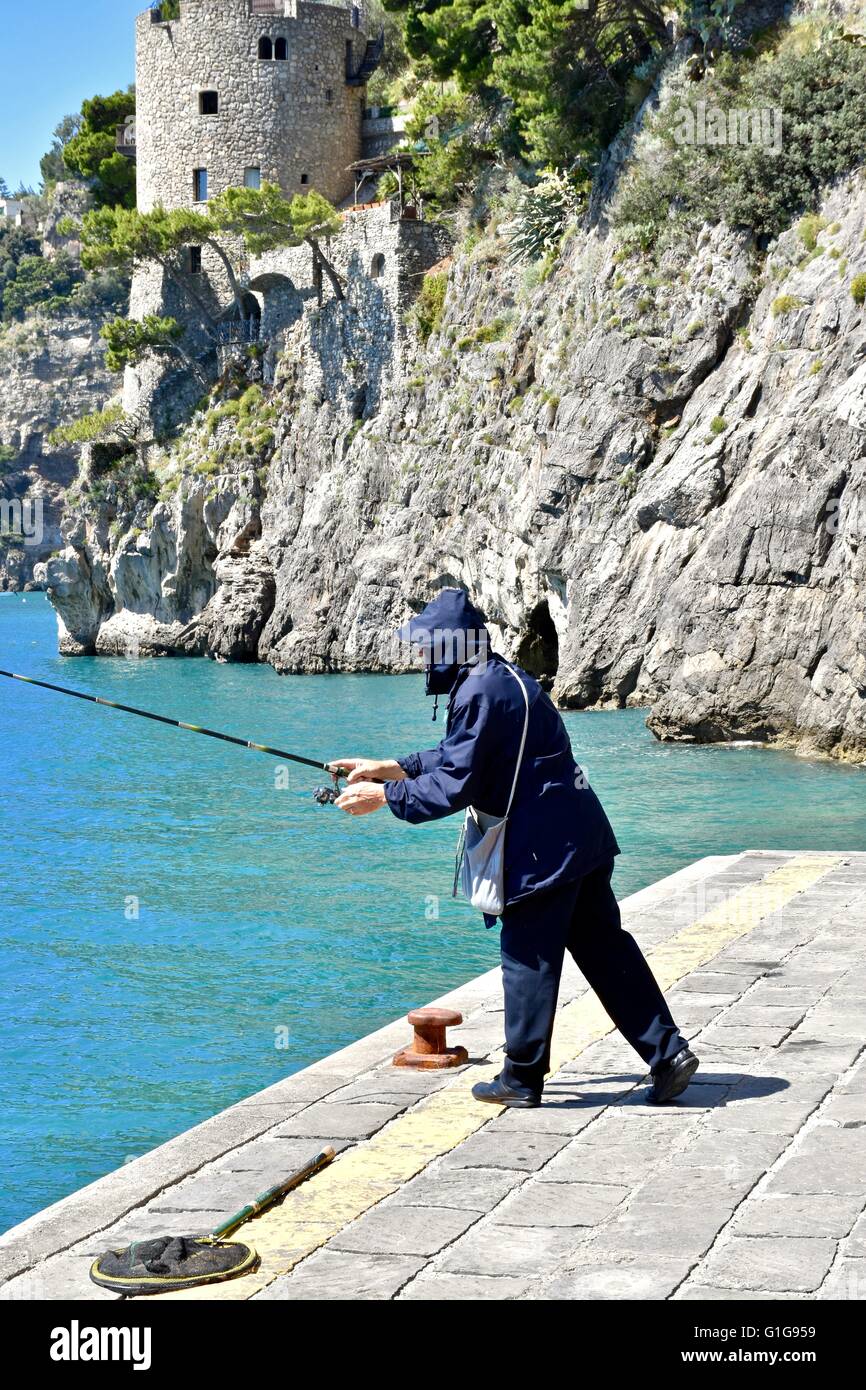 Un uomo con attività di pesca nell'oceano sulla costa amalfitana di Italia Foto Stock