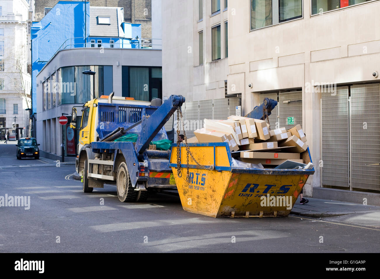 Carrello di prelevare un saltare piena di cartone per il riciclaggio in strada di Londra Foto Stock