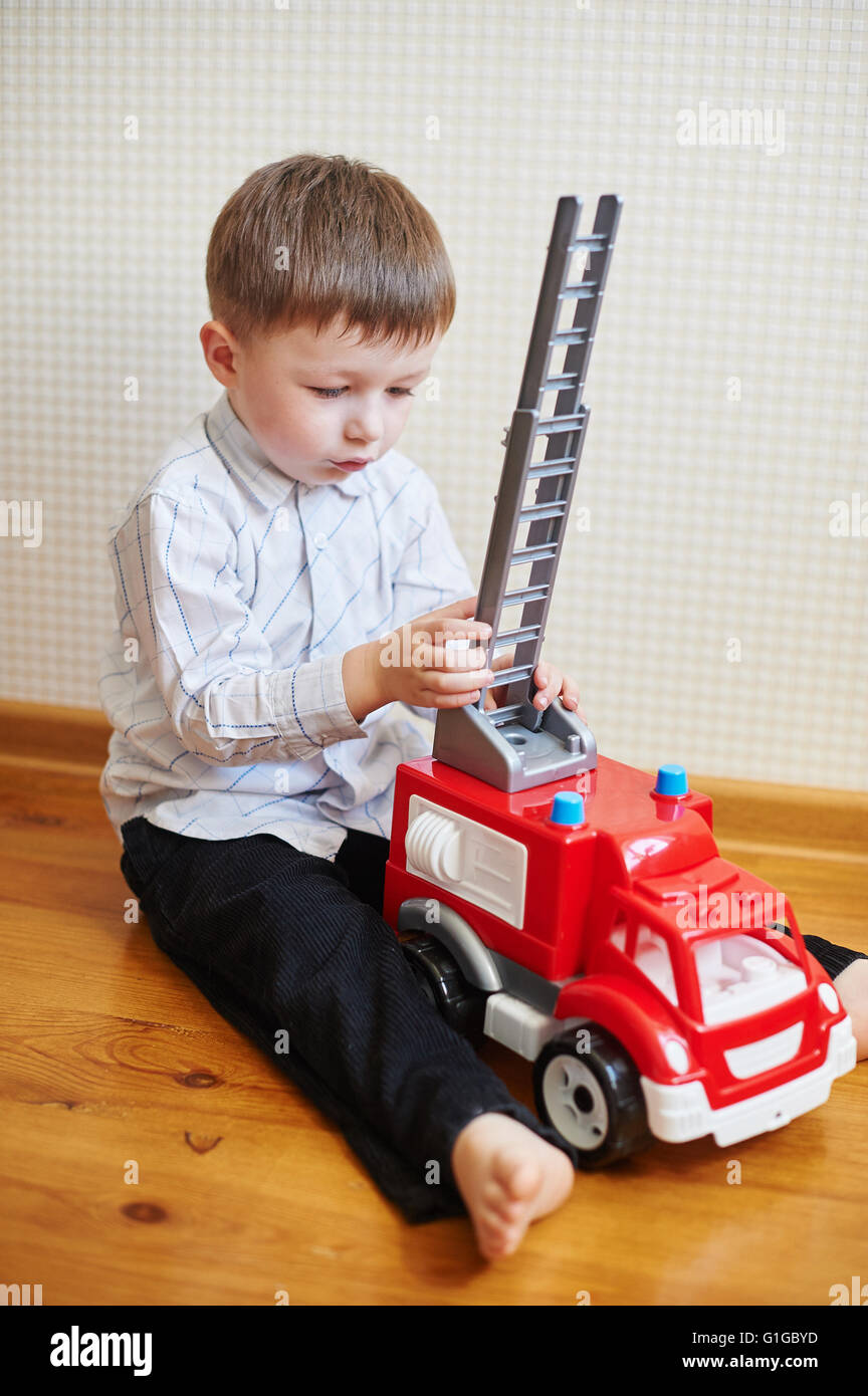 Little Boy giocando rosso macchina giocattolo in camera Foto Stock