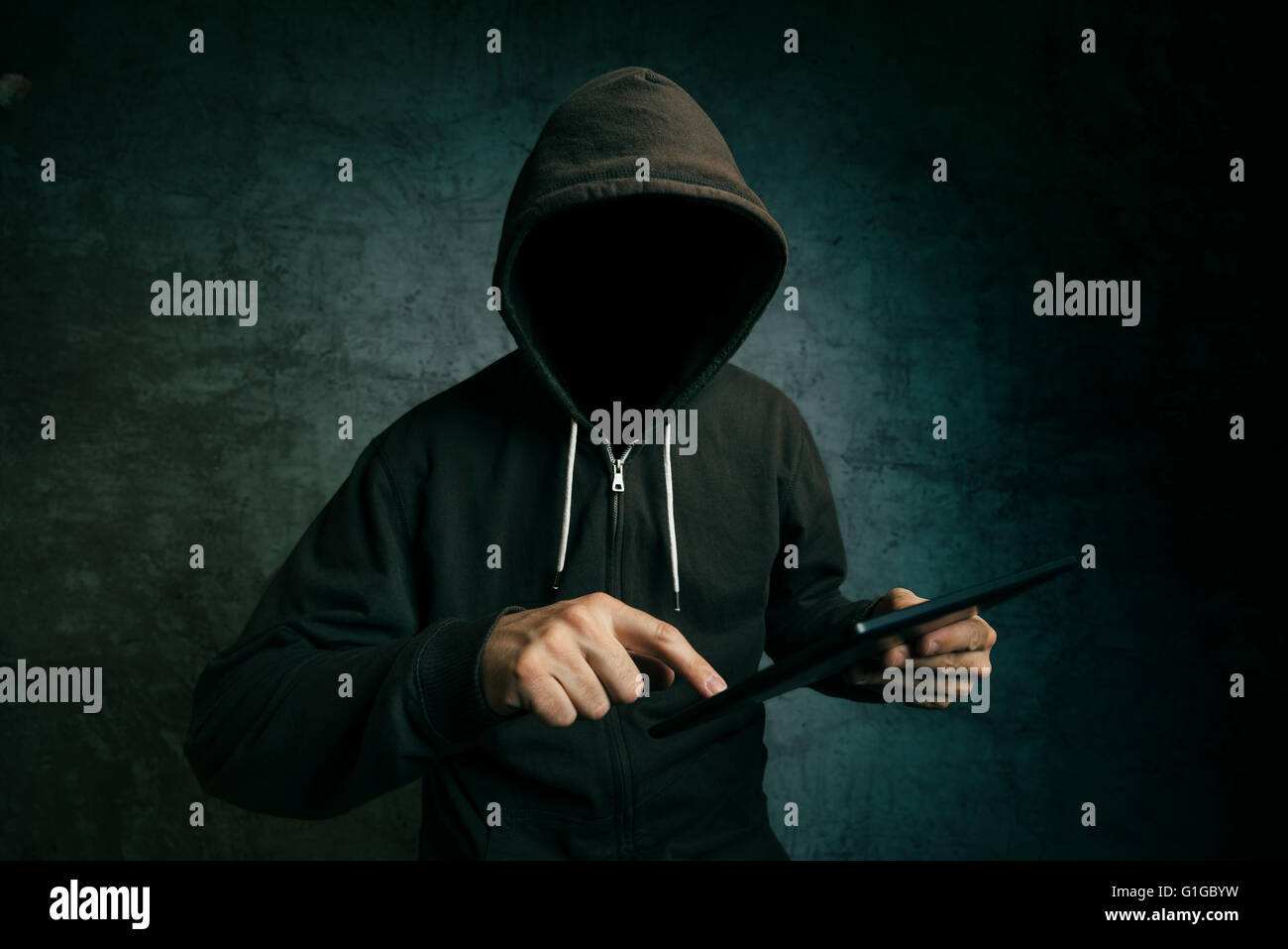 Volto con cappuccio maschio non identificabili persona utilizzando computer tablet, hacker di internet e la sicurezza online concetto. Foto Stock