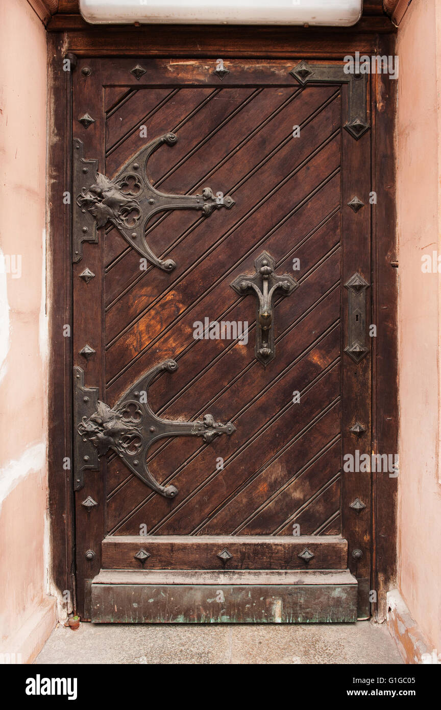 Vecchia porta di legno con tettoie metalliche in edificio storico Foto Stock