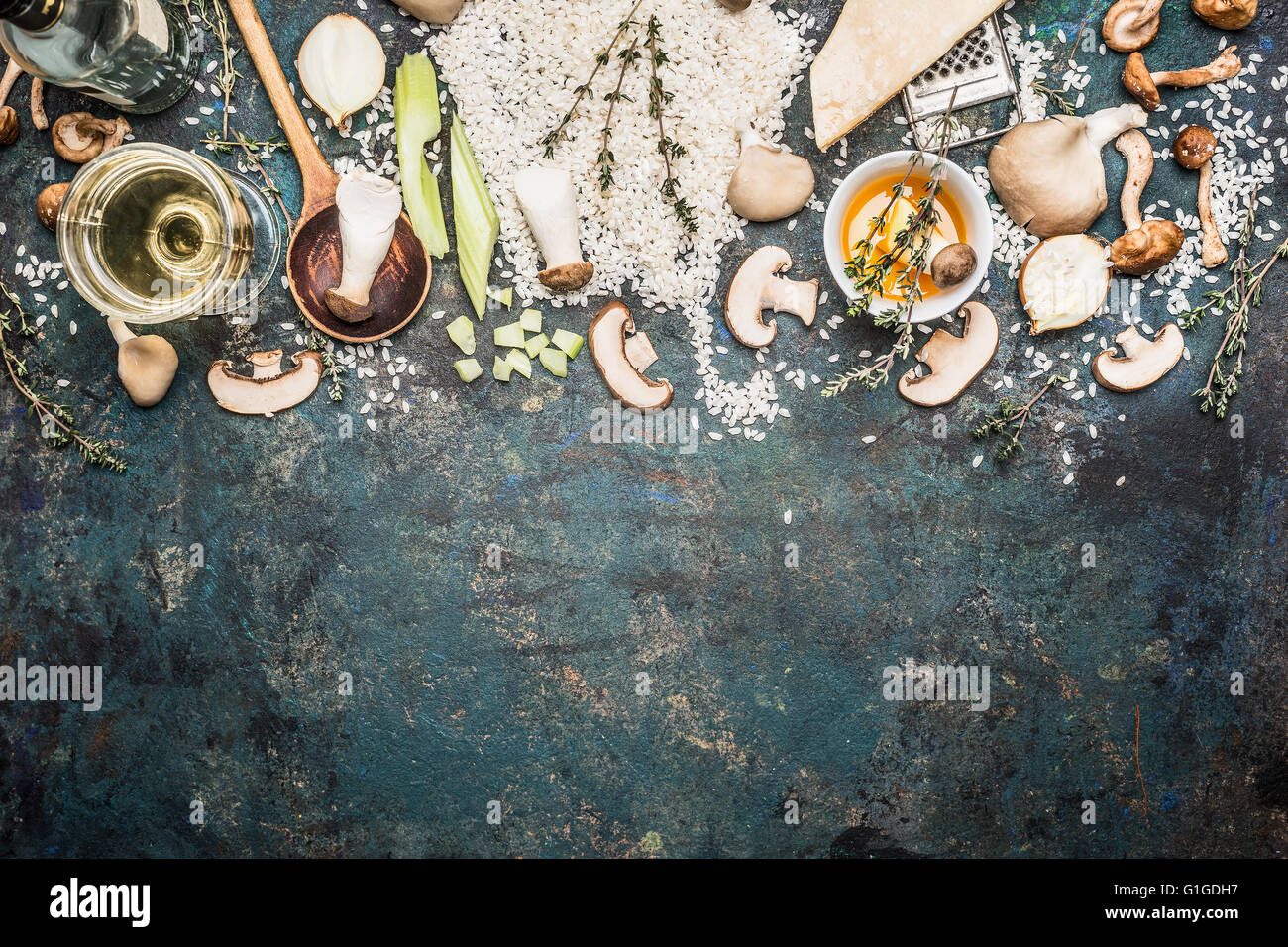 Risotto ai funghi Ingredienti con cucchiaio di cottura su scuro dello sfondo rustico, vista dall'alto, di confine. Il cibo italiano concept Foto Stock