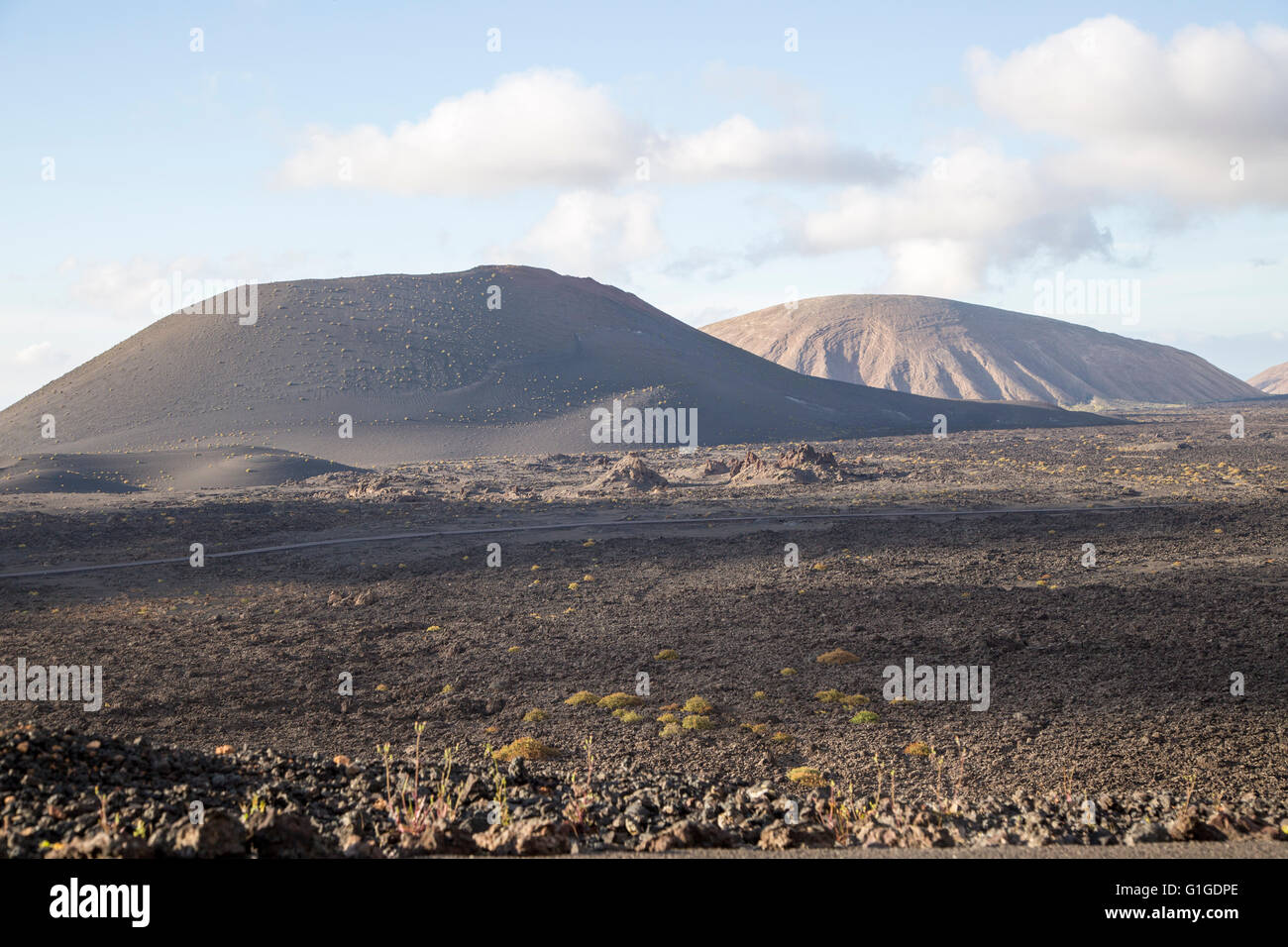 Paesaggio vulcanico di colate di lava solidificata e cono distanti vulcani, vicino a Yaiza, Lanzarote, Isole Canarie, Spagna Foto Stock