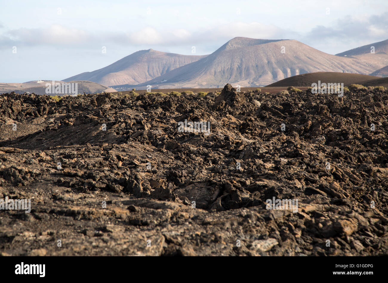 Paesaggio vulcanico di colate di lava solidificata e cono distanti vulcani, vicino a Yaiza, Lanzarote, Isole Canarie, Spagna Foto Stock