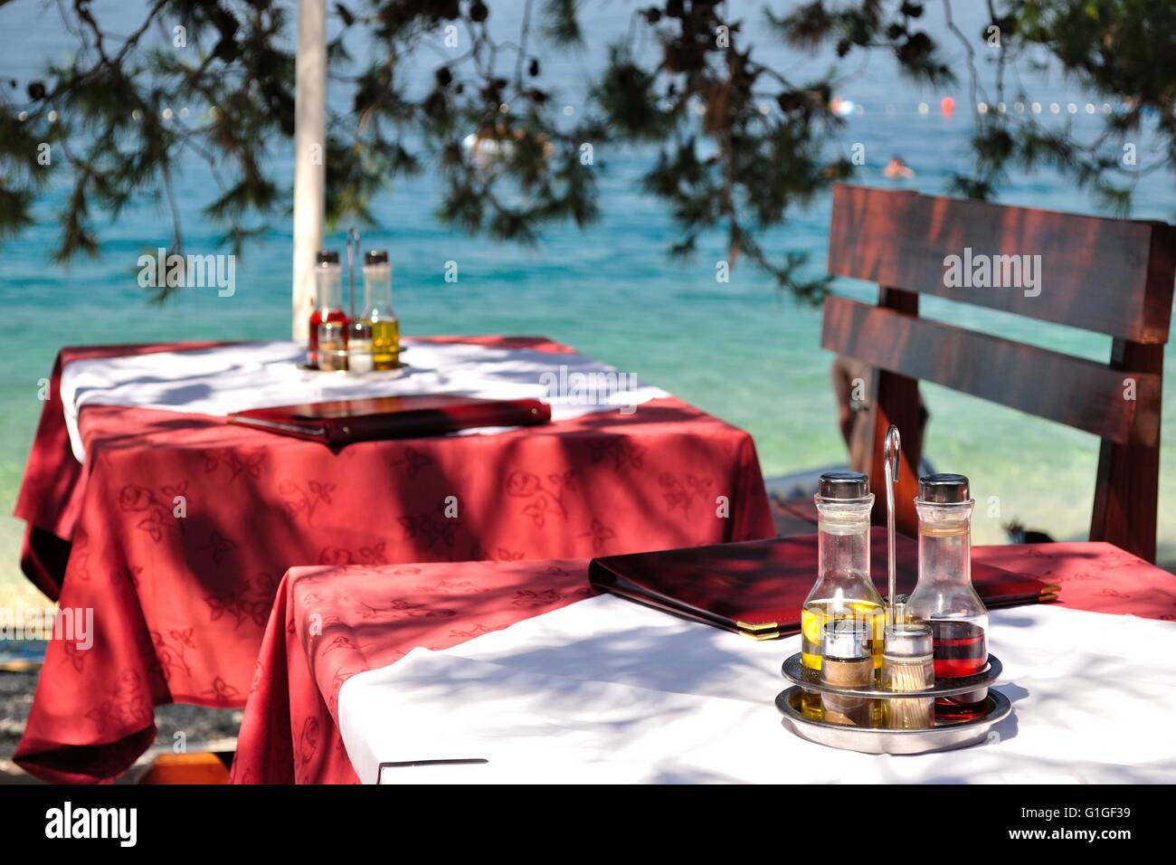 Impostazione tabella con bottiglie di olio di oliva e aceto al Tropical Beach Restaurant, Croazia Foto Stock