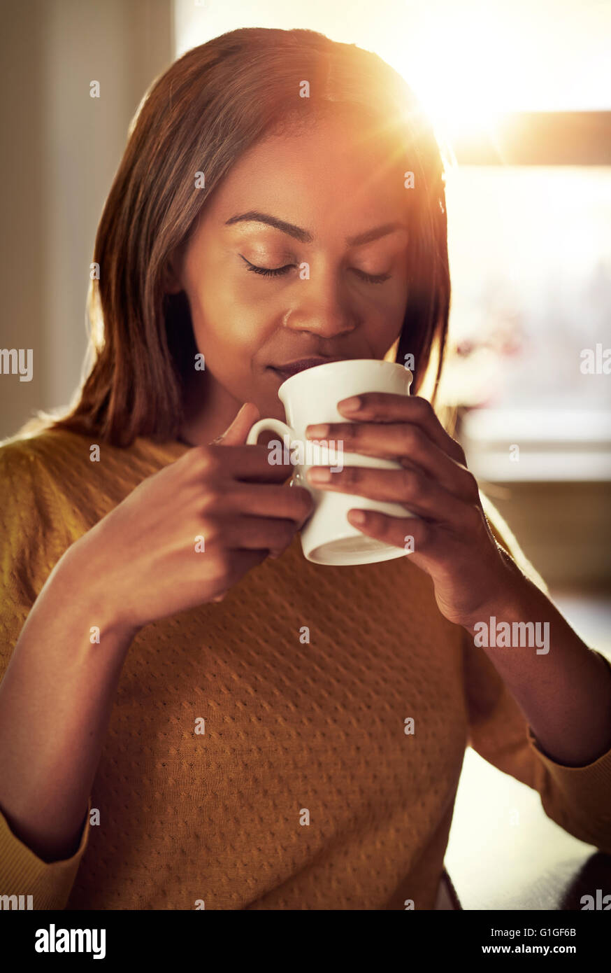 Attraente giovane donna nera di bere una tazza di caffè appena fatto Annusare il profumo con gli occhi chiusi nella Bliss come ella rel Foto Stock