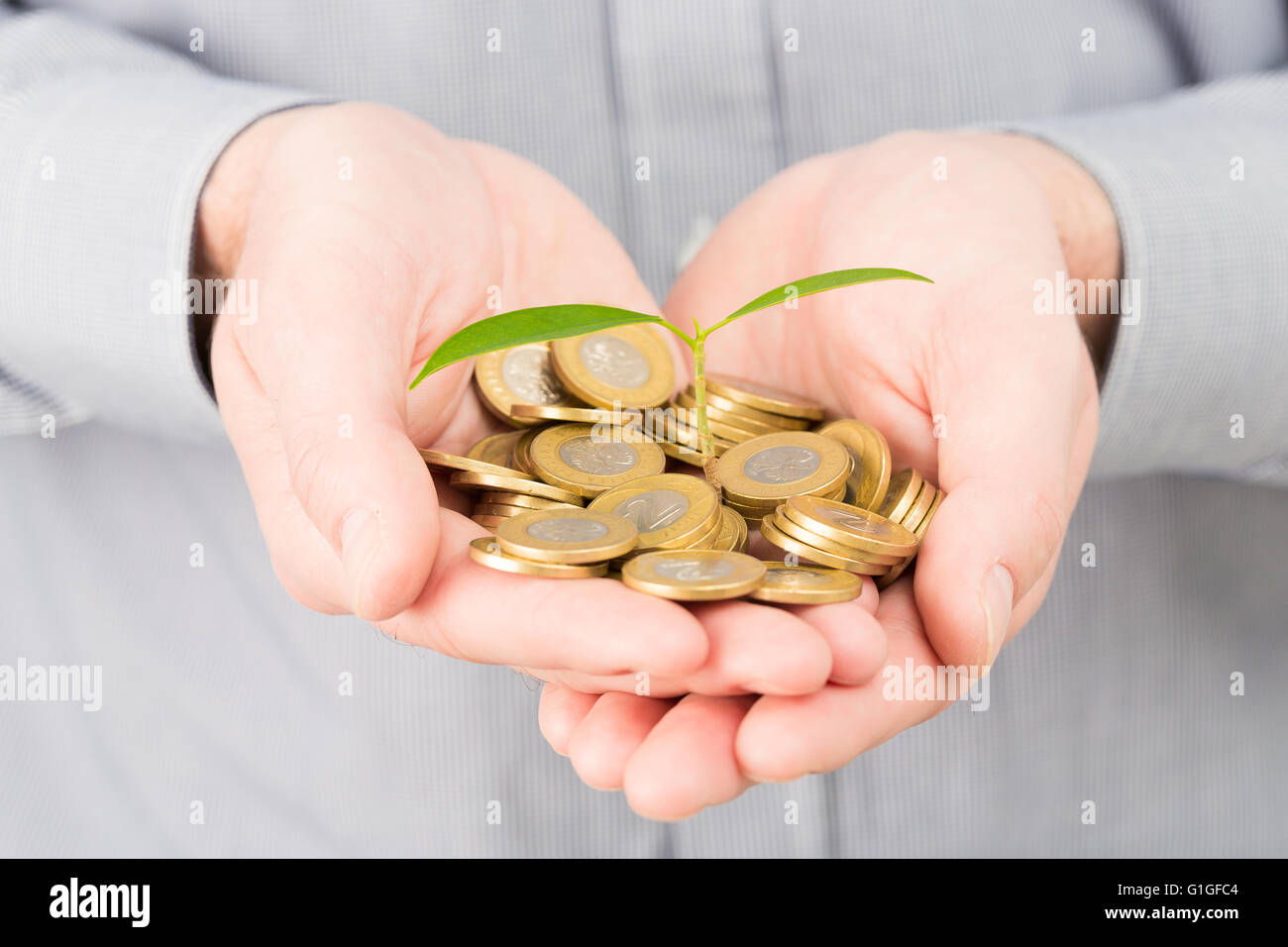 Imprenditore coprire pianta crescente con la medaglia di denaro. Foto Stock