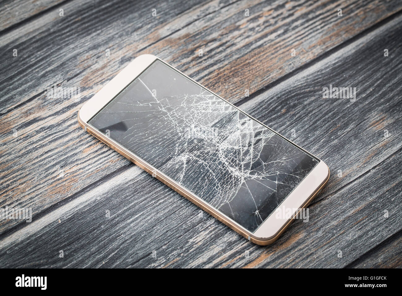 Rotto moderno mobile phone su sfondo di legno. Foto Stock
