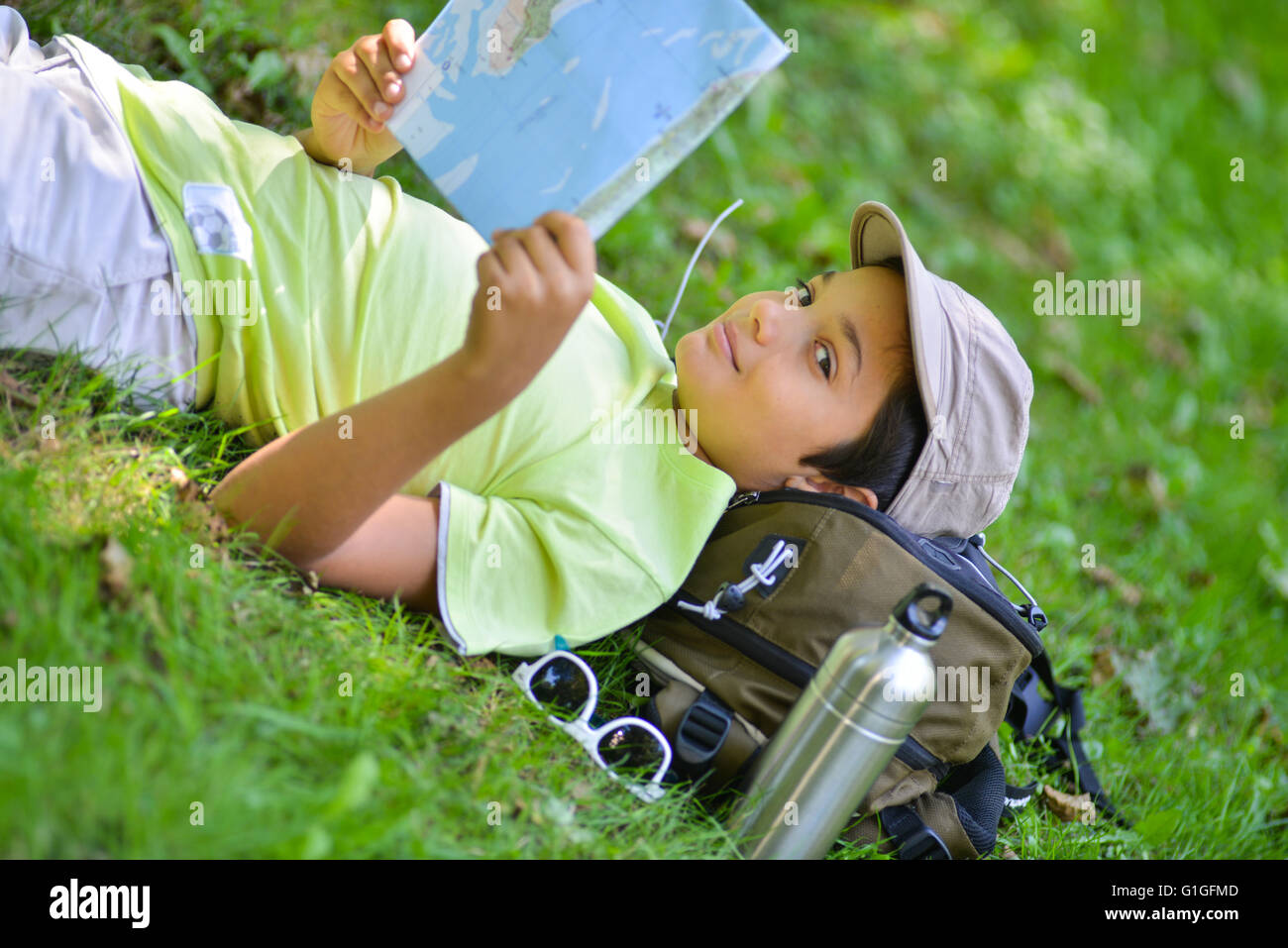 Ragazzo giovane giacente in erba guardando una mappa Foto Stock