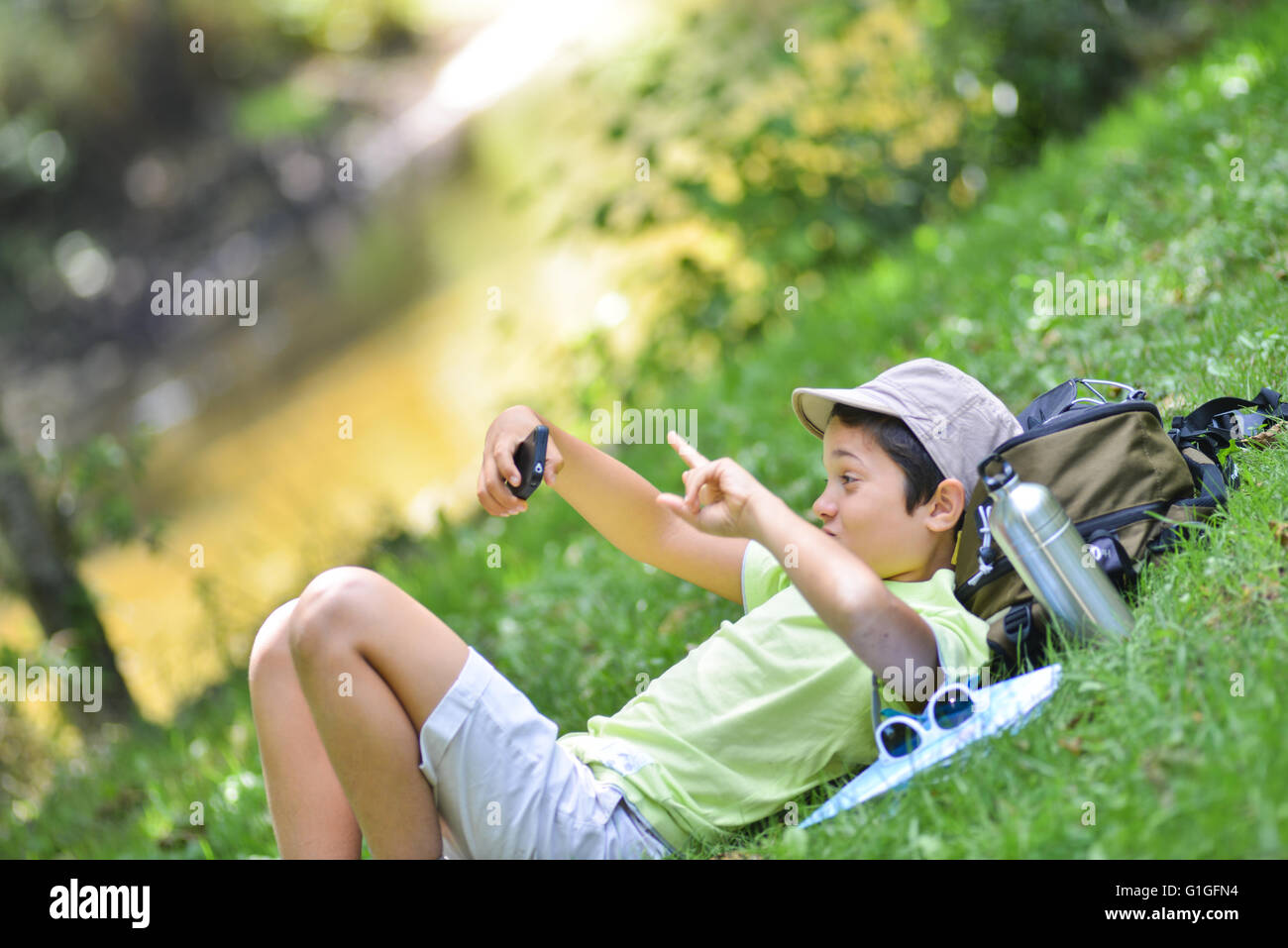 Ragazzo giovane giacente in erba facendo una Selfi con il suo telefono cellulare Foto Stock