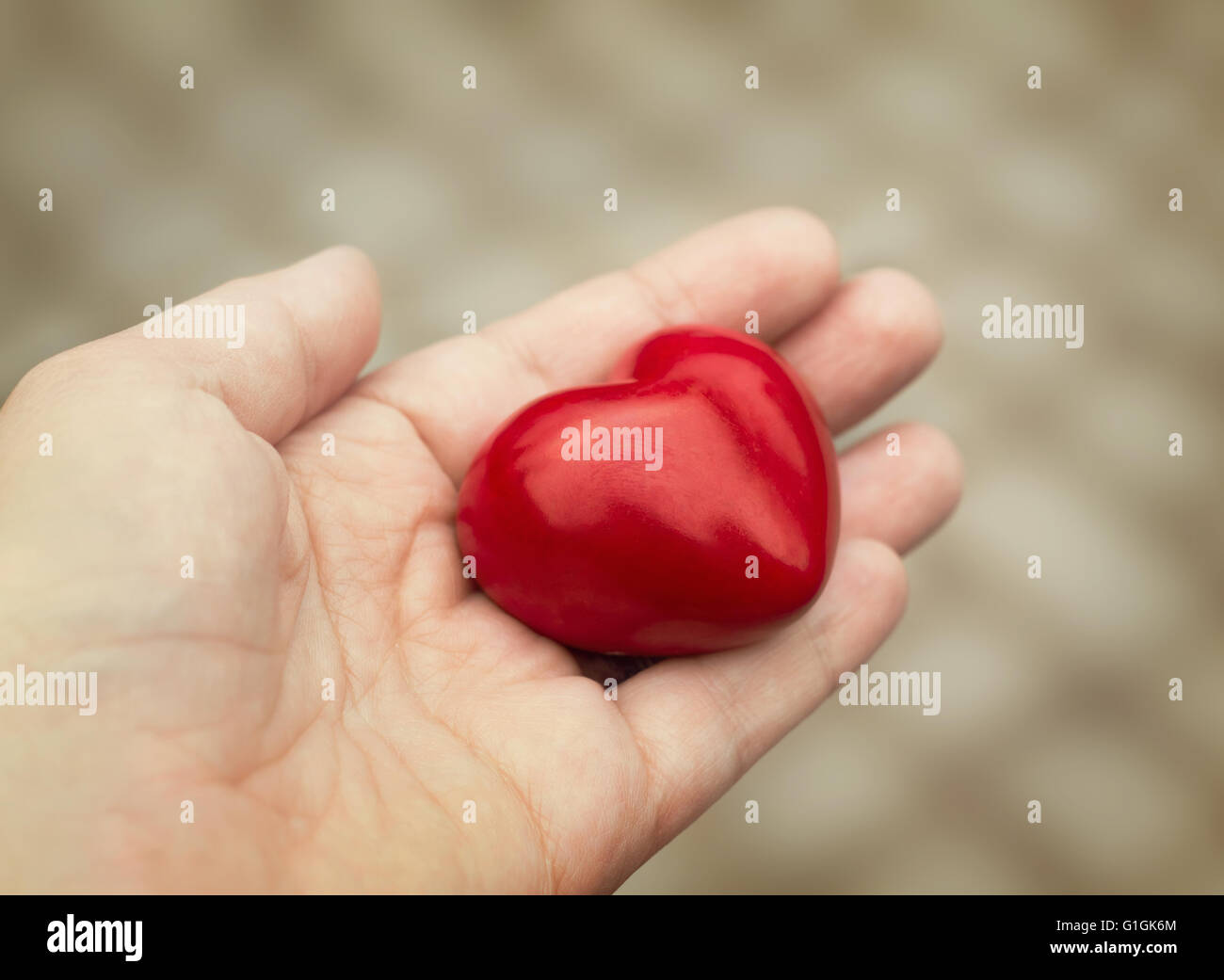 Giovane donna porge un cuore rosso in mano, concetto di amore, di bontà e di empatia Foto Stock