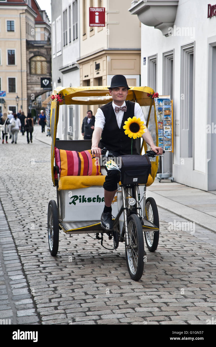Uomo a cavallo di un risciò ciclo taxi lungo una strada di ciottoli di Dresda, in Germania. Foto Stock