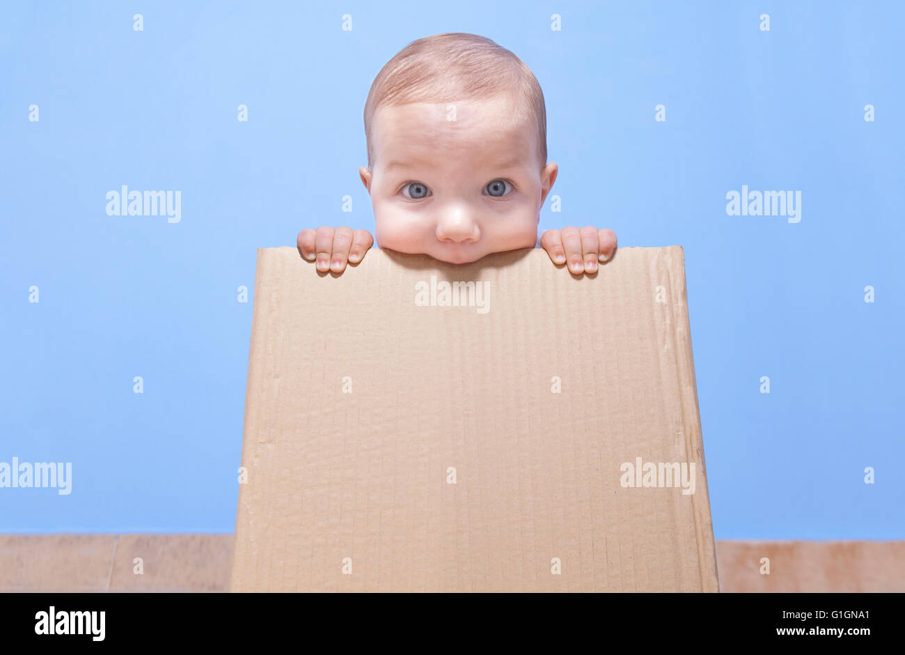 Ritratto di un simpatico baby giocando in un marrone scatola di cartone Foto Stock