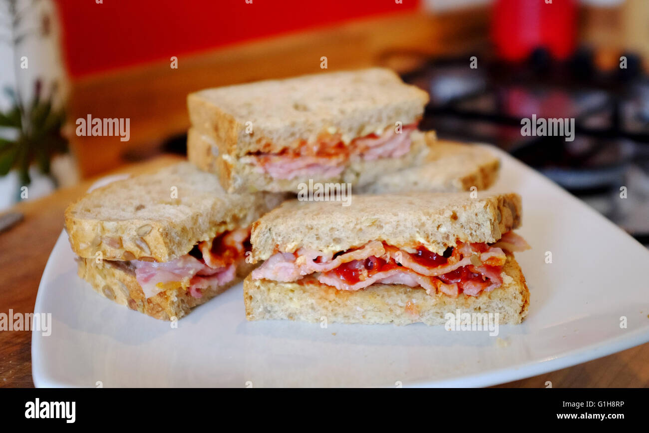 La realizzazione di una pancetta in sandwich di pane integrale con il ketchup o salsa Foto Stock