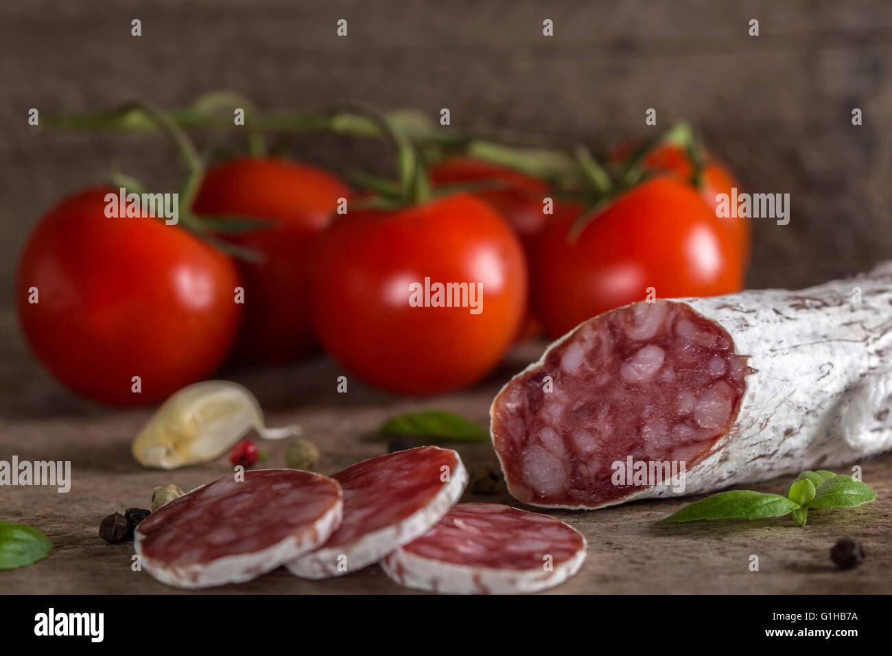 Salame con le spezie e le verdure sopra rustico sfondo di legno Foto Stock