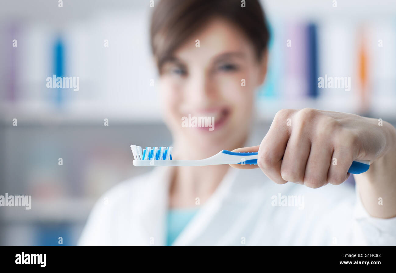 Donna sorridente dentista tenendo uno spazzolino da denti, cure dentarie, igiene e il concetto di prevenzione Foto Stock