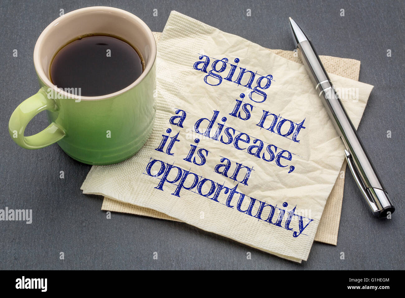 L'invecchiamento non è una malattia ma è una opportunità - scrittura su un tovagliolo con una tazza di caffè espresso Foto Stock