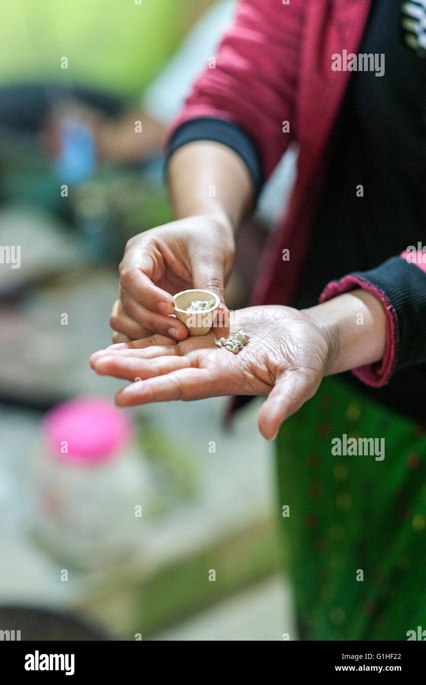 Argento che è fatto in gioielli in un laboratorio di argento sul lago Inle,  Myanmar. La donna sta tenendo un pezzo di minerale da cui fare l'argento  nelle sue mani Foto stock -