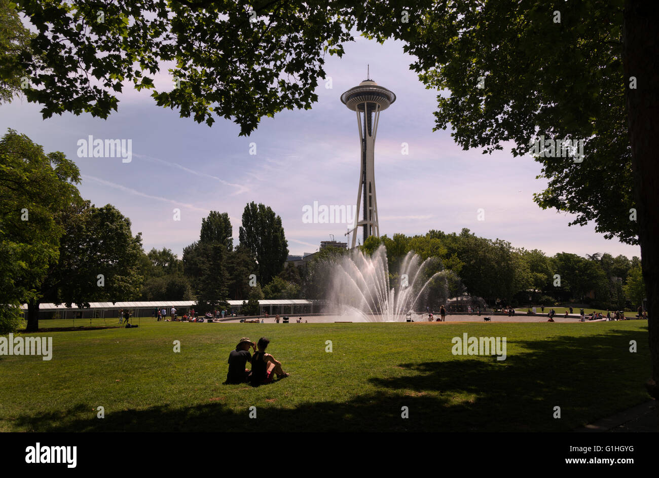 Un giovane si siede nel prato vicino alla fontana internazionale e lo Space Needle a Seattle, Washington, USA (Adrien Veczan) Foto Stock