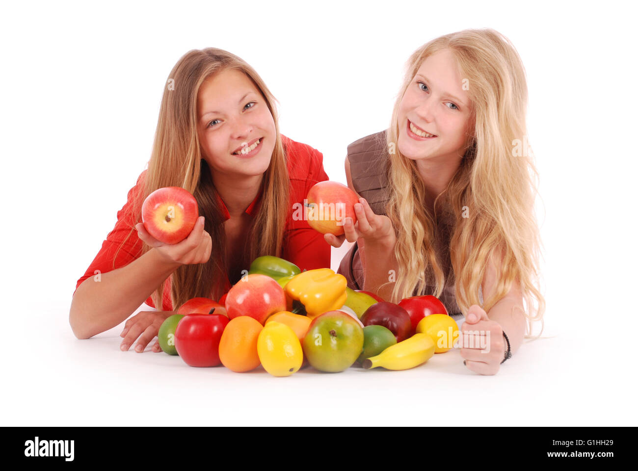 Due ragazze azienda frutta fresca isolato su bianco Foto Stock