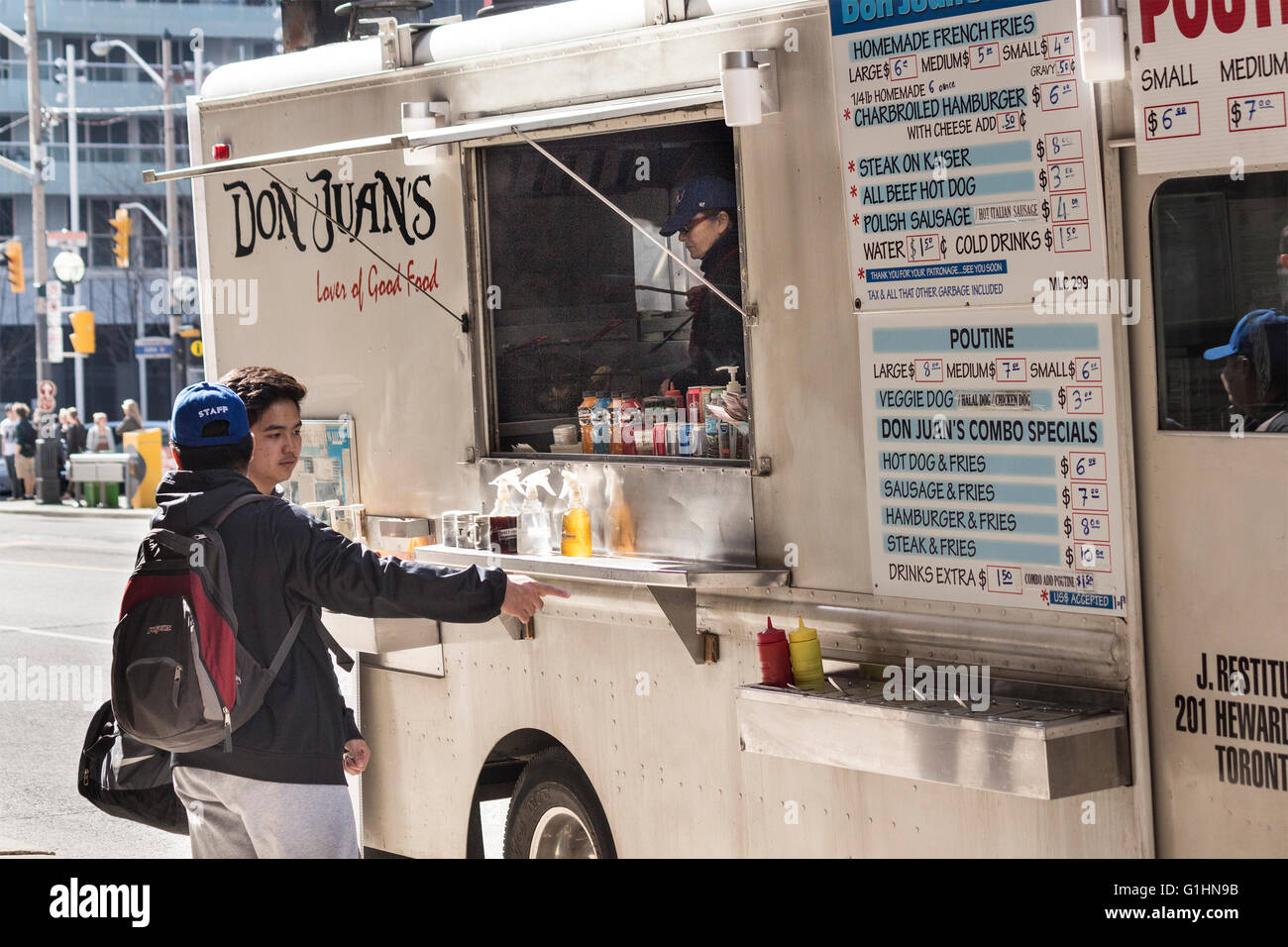 I clienti maschi ordinazione presso un cibo carrello nel centro cittadino di Toronto, Ontario, Canada Foto Stock