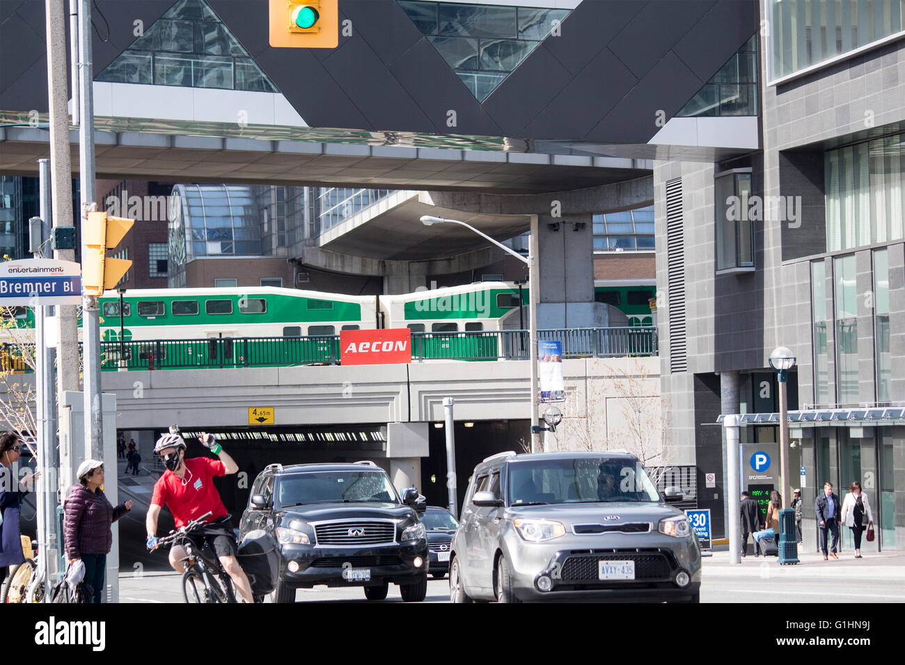 Andare il treno viaggia su abbassare Simcoe St. a Bremmer Blvd con pendolari in auto, in bicicletta e a piedi Foto Stock