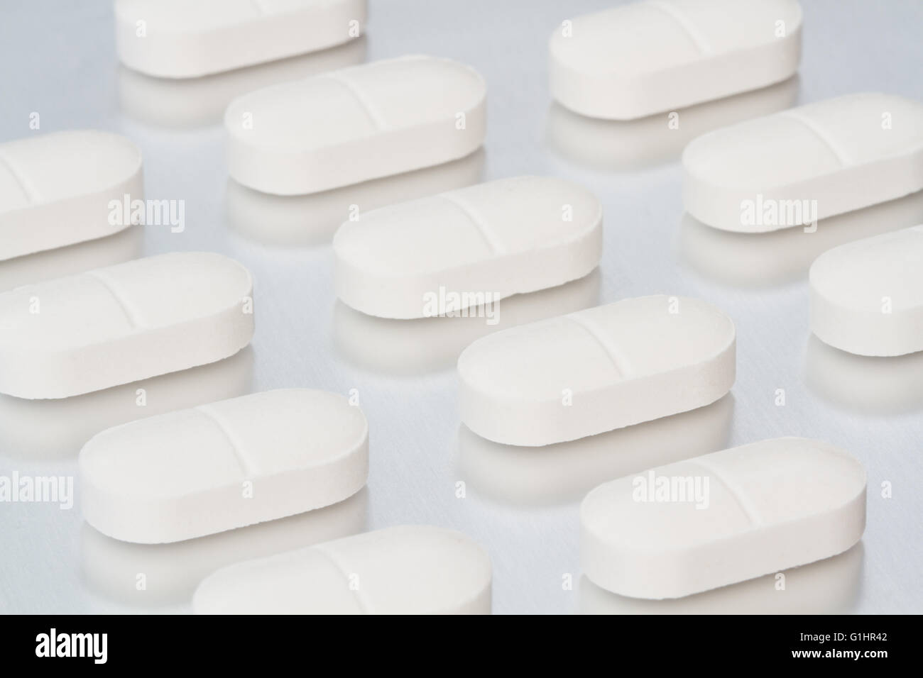 Righe di bianco, sollievo dal dolore compresse su un lucido superficie metallica in una fabbricazione farmaceutica dell'immagine. Foto Stock