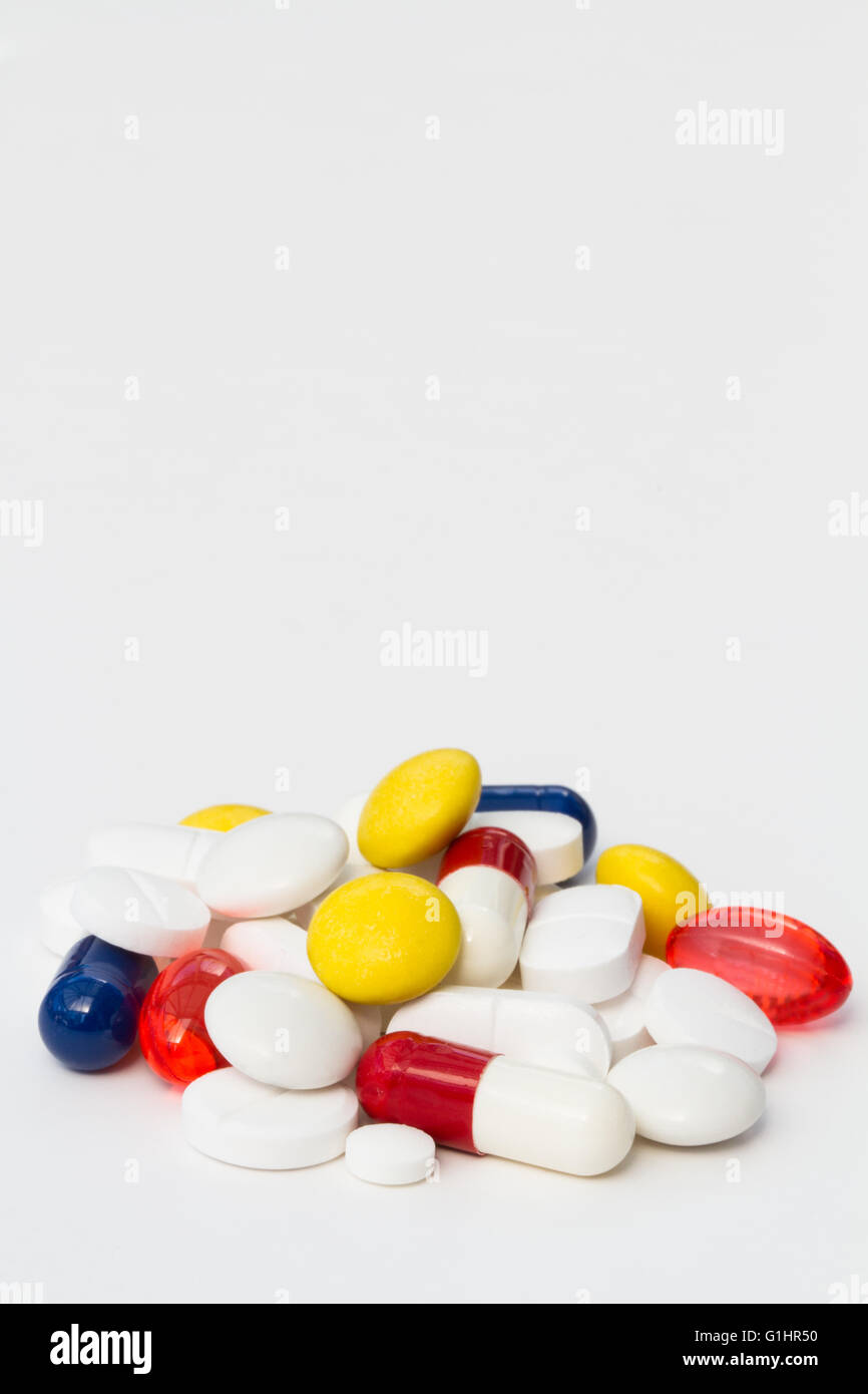 Un mucchio di differenti, varia e colorata pillole, compresse e farmaci isolato su un fondo bianco. Orientamento verticale. Foto Stock