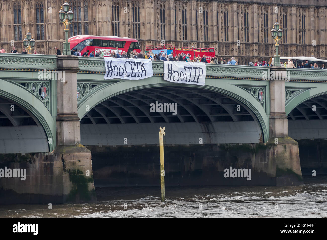 Londra, Regno Unito. 16 Maggio, 2016. Come parte di una giornata di protesta contro il Canada/UE e UA/UE trattative commerciali in corso di negoziato in segreto, attivisti banner abbassata sul Westminster Bridge con i messaggi '#noCETA #noTTIP' e '#noCETA Hands Off la democrazia'. Anche i parlamentari che sono mantenuti al buio circa i dettagli di queste trattative e il parlamento del Regno Unito sarà quasi certamente non può essere consentito di votare su di essi; è la sola Unione europea Parlamento europeo che non è in grado di porre il veto CETA o TTIP. Peter Marshall / Alamy Live News Foto Stock