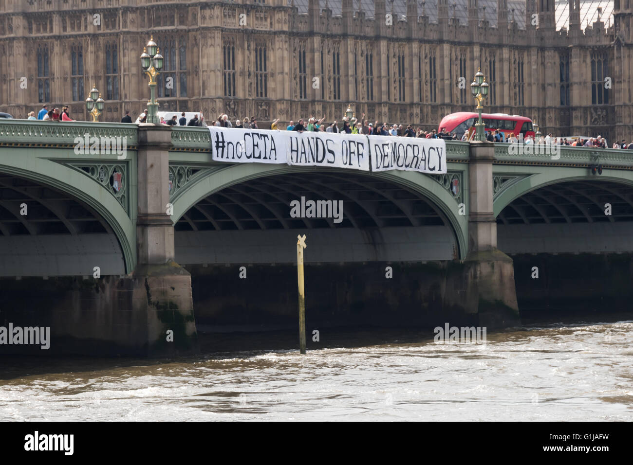 Londra, Regno Unito. 16 Maggio, 2016. Come parte di una giornata di protesta contro il Canada/UE e UA/UE trattative commerciali in corso di negoziato in segreto, attivisti banner abbassata sul Westminster Bridge con i messaggi '#noCETA #noTTIP' e '#noCETA Hands Off la democrazia'. Anche i parlamentari che sono mantenuti al buio circa i dettagli di queste trattative e il parlamento del Regno Unito sarà quasi certamente non può essere consentito di votare su di essi; è la sola Unione europea Parlamento europeo che non è in grado di porre il veto CETA o TTIP. Peter Marshall / Alamy Live News Foto Stock