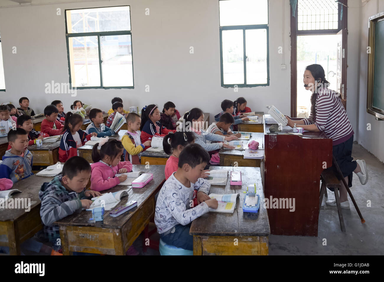 (160517) -- FENGTAI, 17 maggio 2016 (Xinhua) -- Li Yuanfang mette la sua gamba sinistra su una panchina per alleviare il dolore mentre dando classe Zhangxiang presso la scuola elementare nel Dingji città di Fengtai County, est cinese della provincia di Anhui, 16 maggio 2016. Il 42-anno-vecchio insegnante femminile, che hanno sofferto la poliomielite in tre, ha mantenuto sulla classe che dà sul bastone per diciotto anni poiché la sua laurea nel 1998. Per anni ha riposare per almeno quattro ore ogni giorno, che rende i suoi afflitti da dolore in vita ed estremità inferiori. " Ho pensato che il mio corpo condizione potrebbe non fare di me un insegnante, ma finalmente ho trovato è Foto Stock
