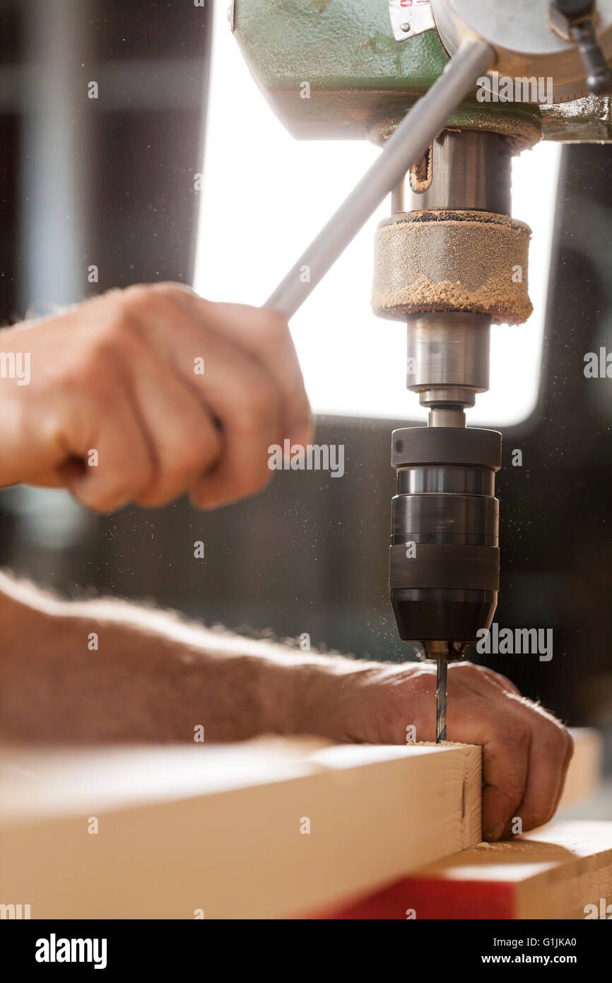 Falegname la perforazione di un listone con macchinari nel suo laboratorio Foto Stock