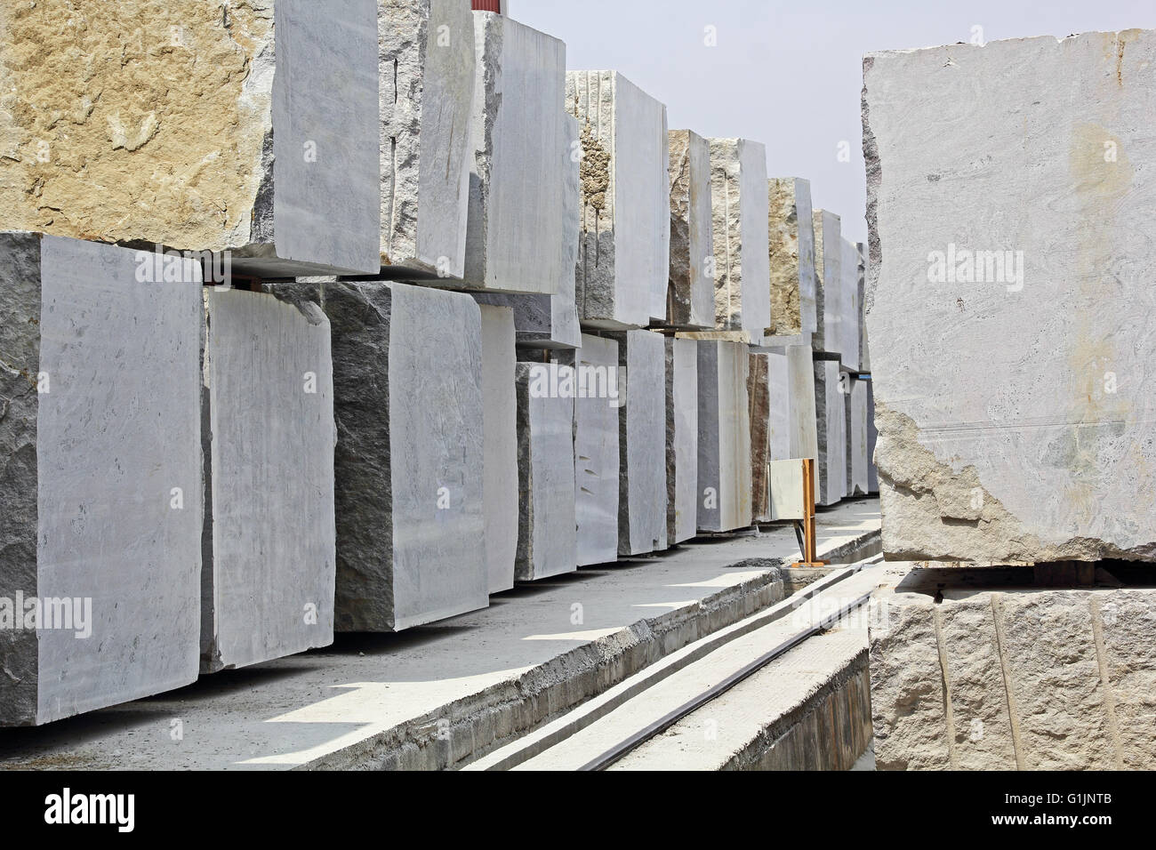 Enormi blocchi di granito impilati in una pietra fabbrica di lavorazione per il taglio e la lucidatura di pavimenti in lastre utilizzato nella costruzione di edifici Foto Stock