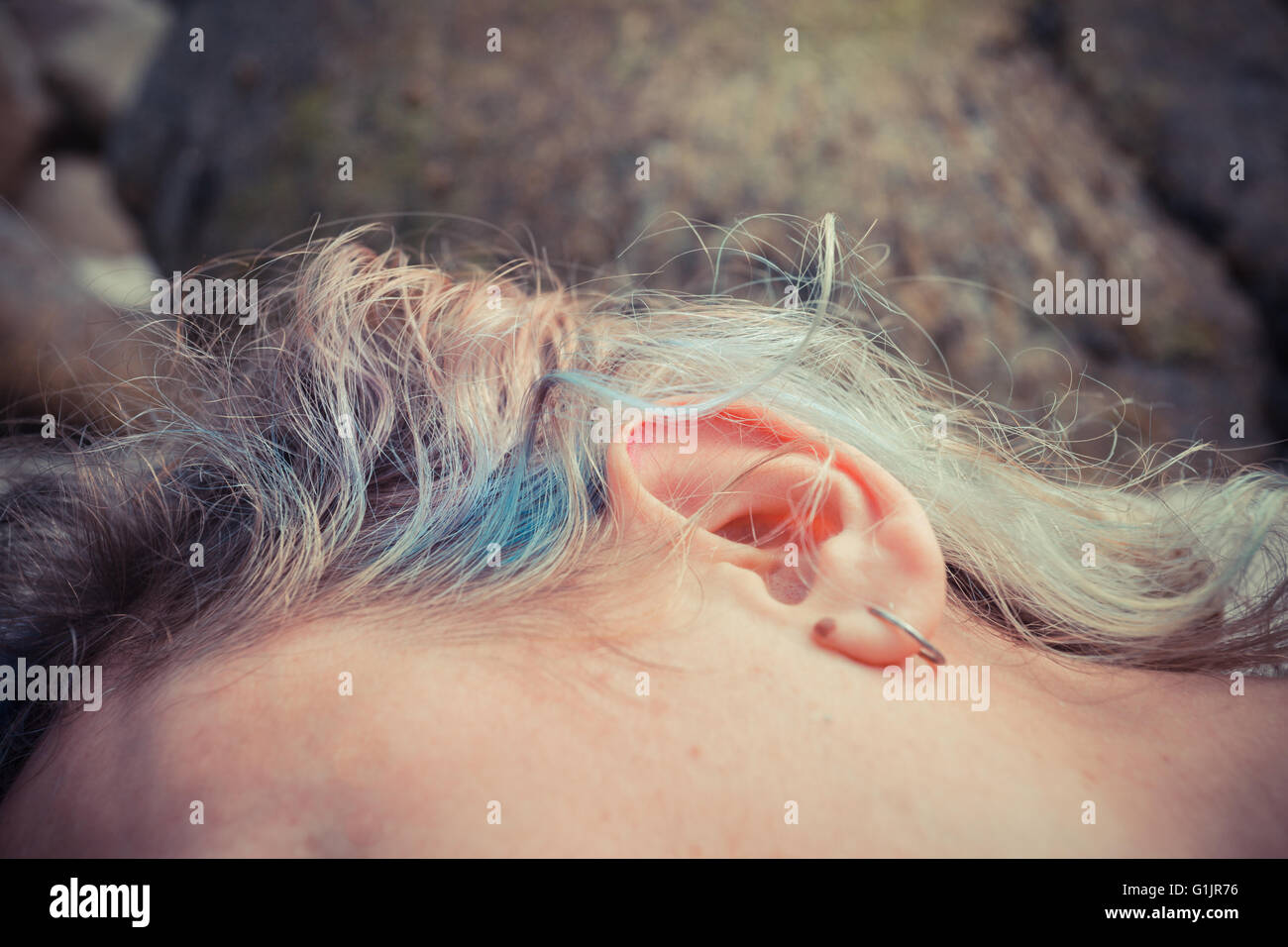 Primo piano su una giovane donna di orecchio come ella è giacente al di fuori Foto Stock