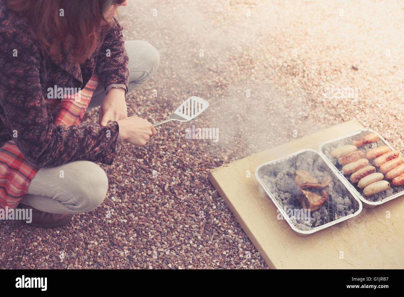 Una giovane donna è la cottura della carne su un barbecue Foto Stock