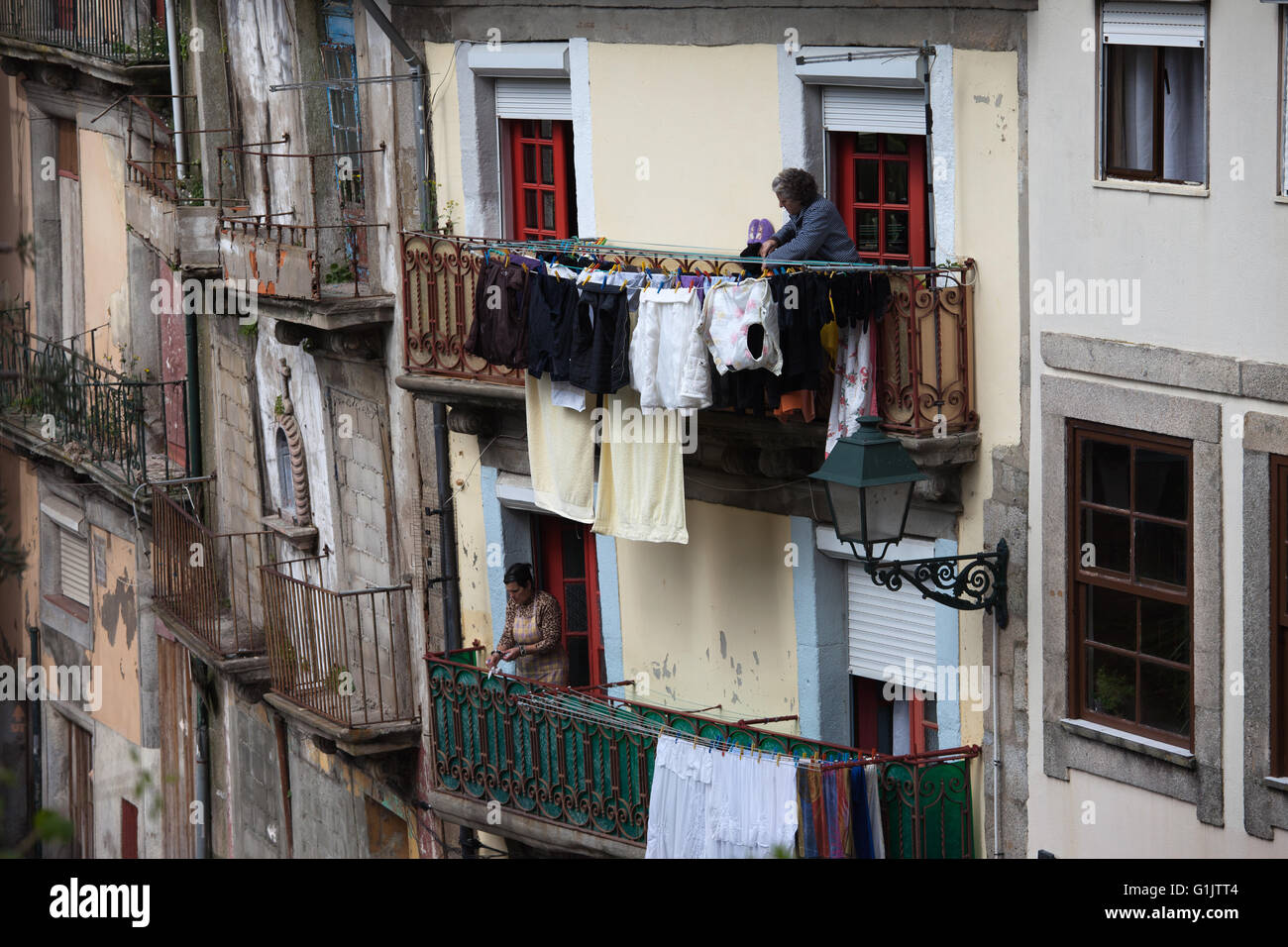 Il Portogallo, città di Porto, donne panni appesi per asciugare sul balcone della casa, quotidiana attività di routine Foto Stock