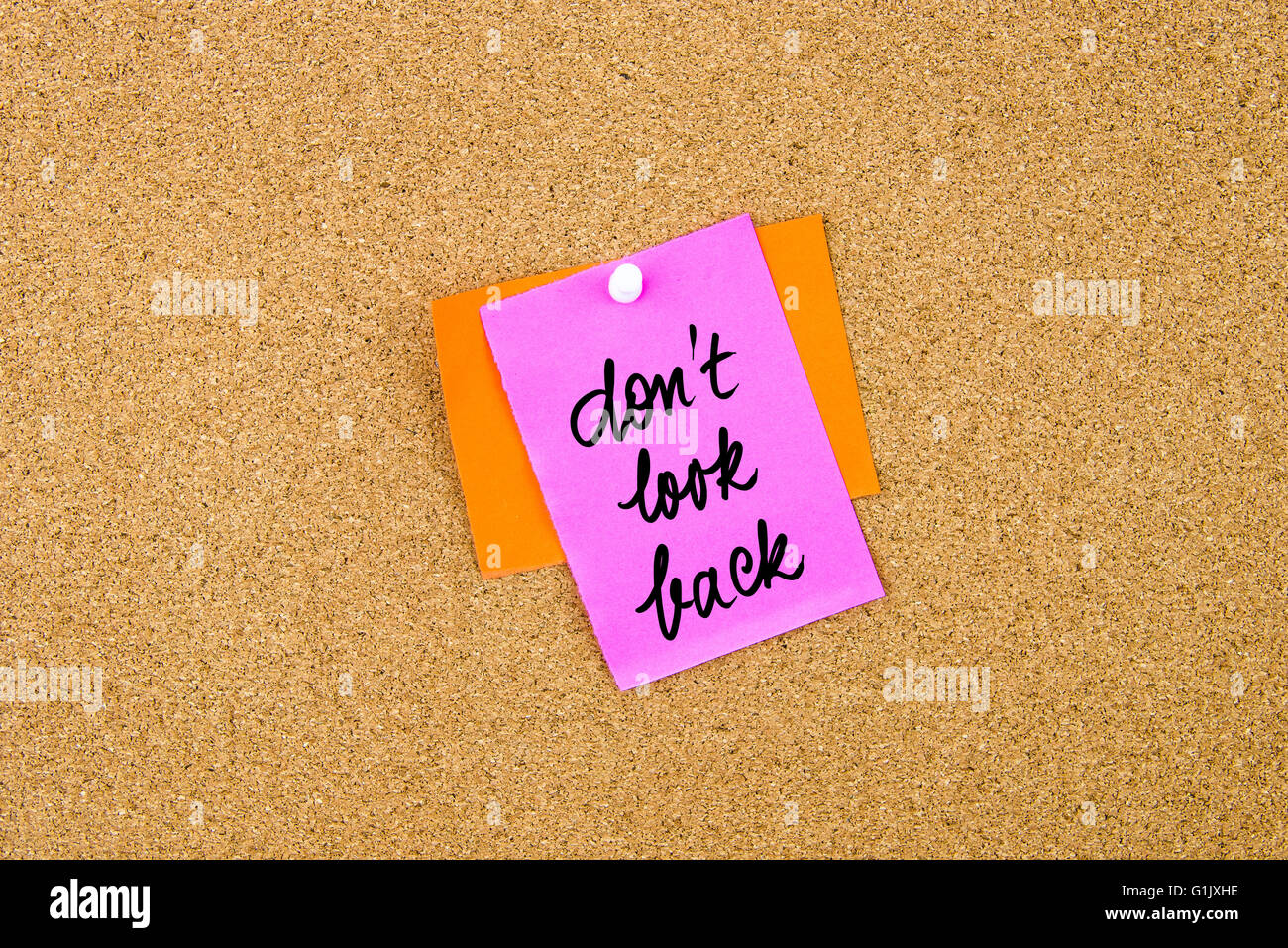 Non guardare indietro scritto su carta nota appuntata sulla bacheca di sughero con la puntina bianca, copia dello spazio disponibile Foto Stock