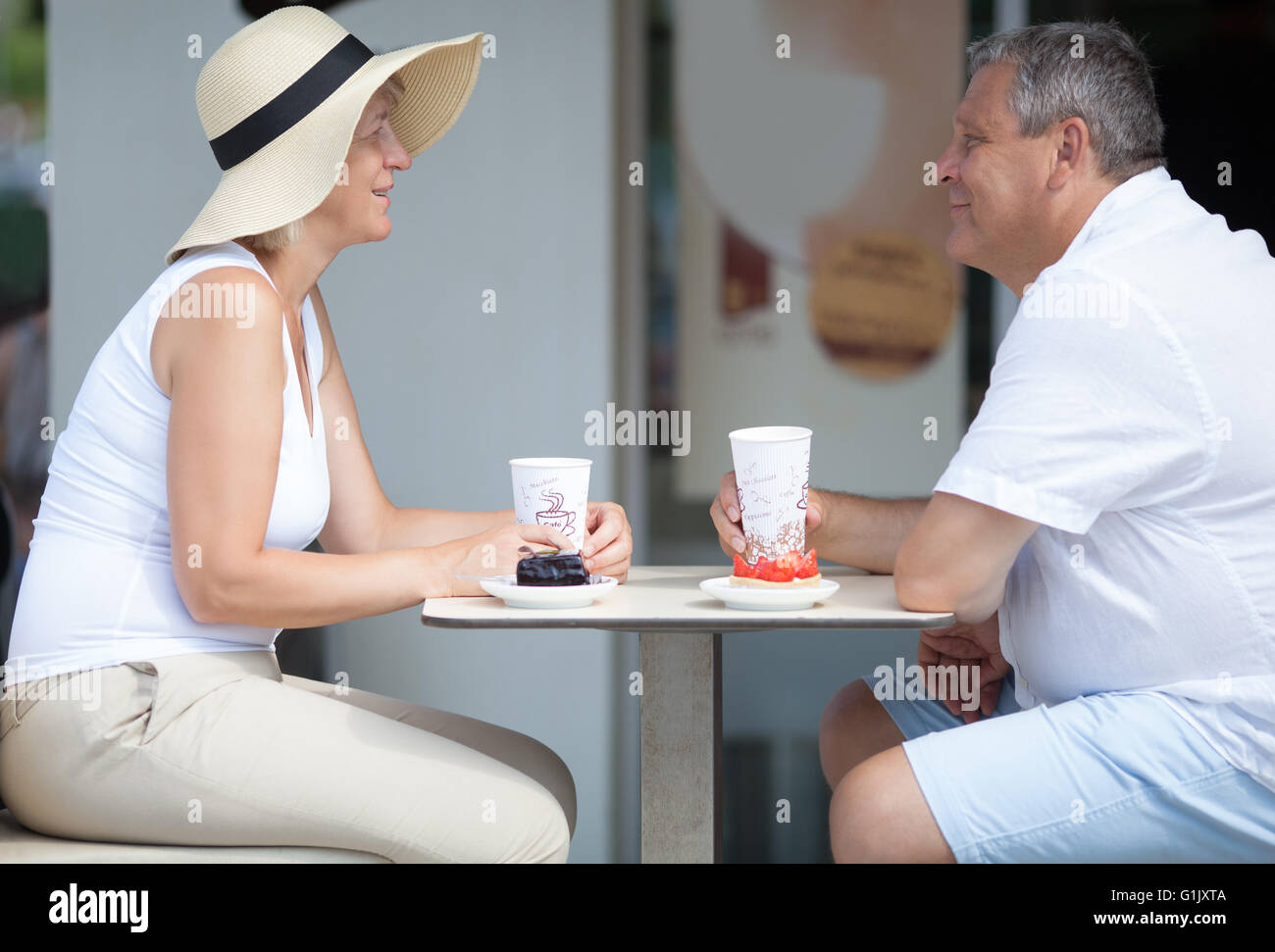 Vista laterale di due sorridere persone anziane in outdoor cafe Foto Stock