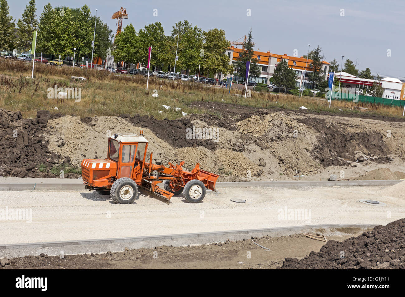 Motolivellatrice sta lavorando sul livellamento di ghiaia per la nuova strada sul sito in costruzione. Foto Stock