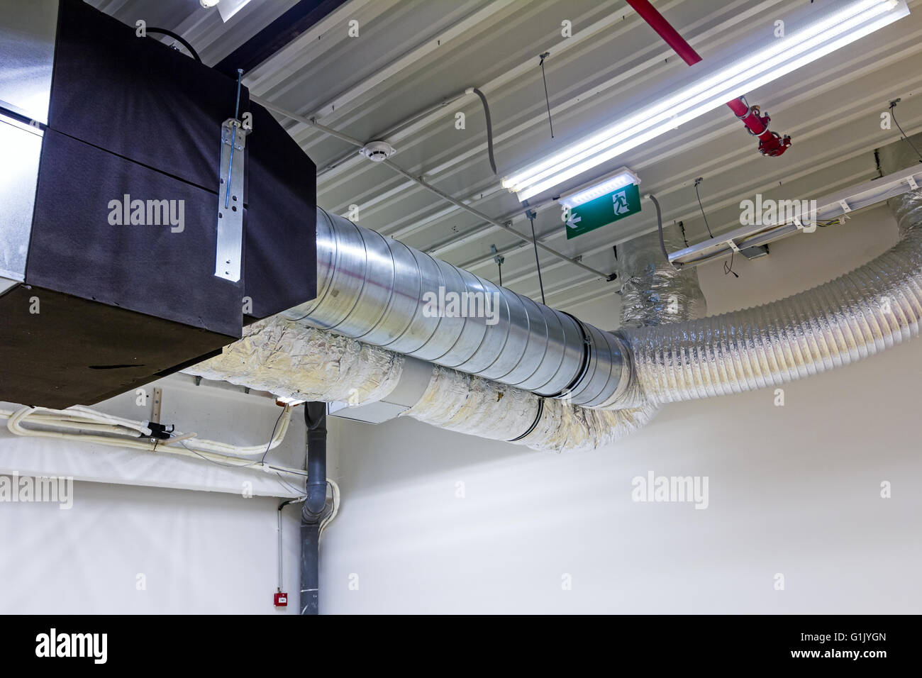 Soffitto con tubi di ventilazione per l'aria condizionata e fire exit segno. Foto Stock