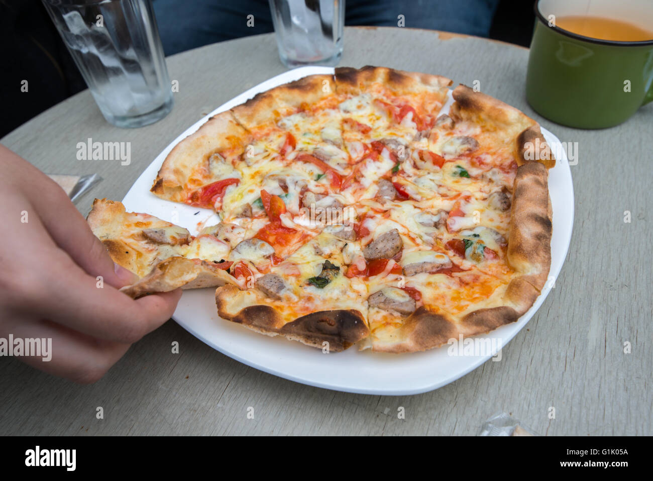 Una piccola pizza sulla piastra con il pezzo in presa Foto Stock