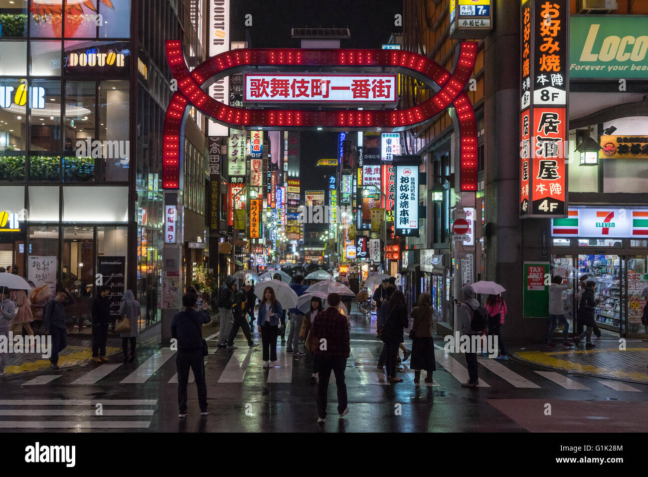 La gente a piedi di notte sotto la pioggia di Kabukicho, quartiere a luci rosse di Shinjuku, Tokyo, Giappone Foto Stock