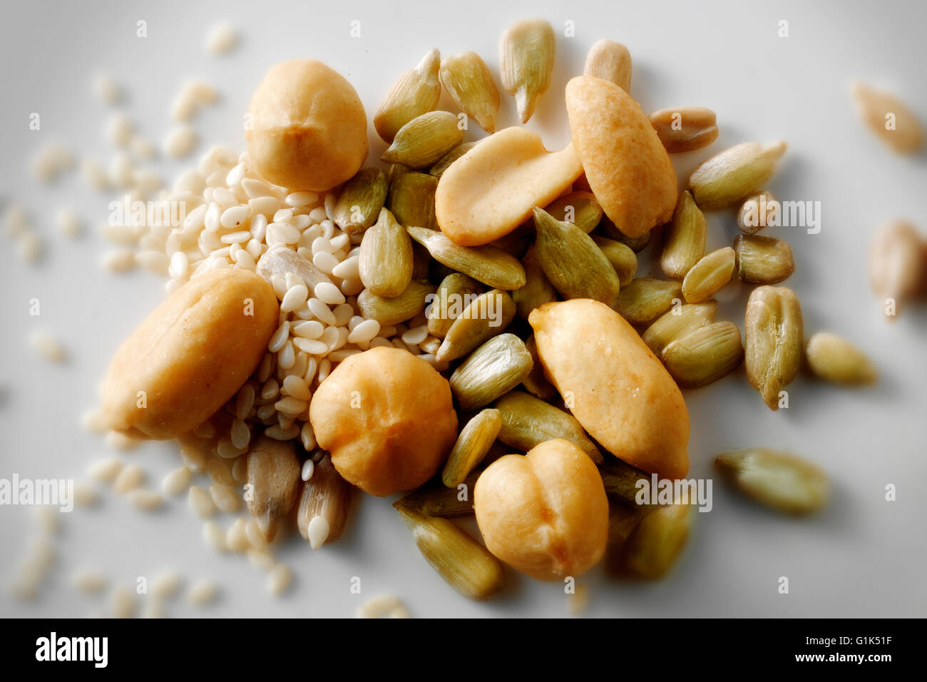 Un sano mix di arachidi, olio di semi di girasole, le nocciole e i semi di sesamo contro uno sfondo bianco, close up top shot Foto Stock