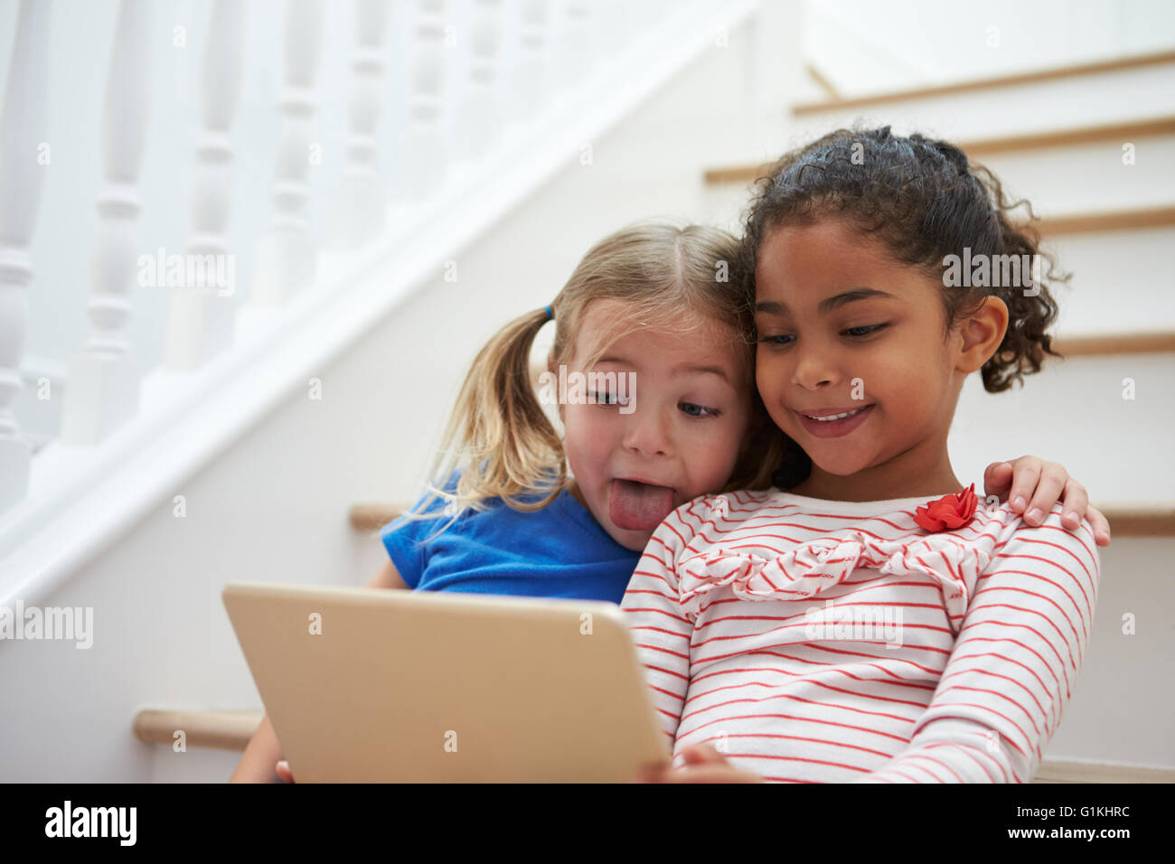 Due ragazze in posa per Selfie sulla tavoletta digitale in casa Foto Stock