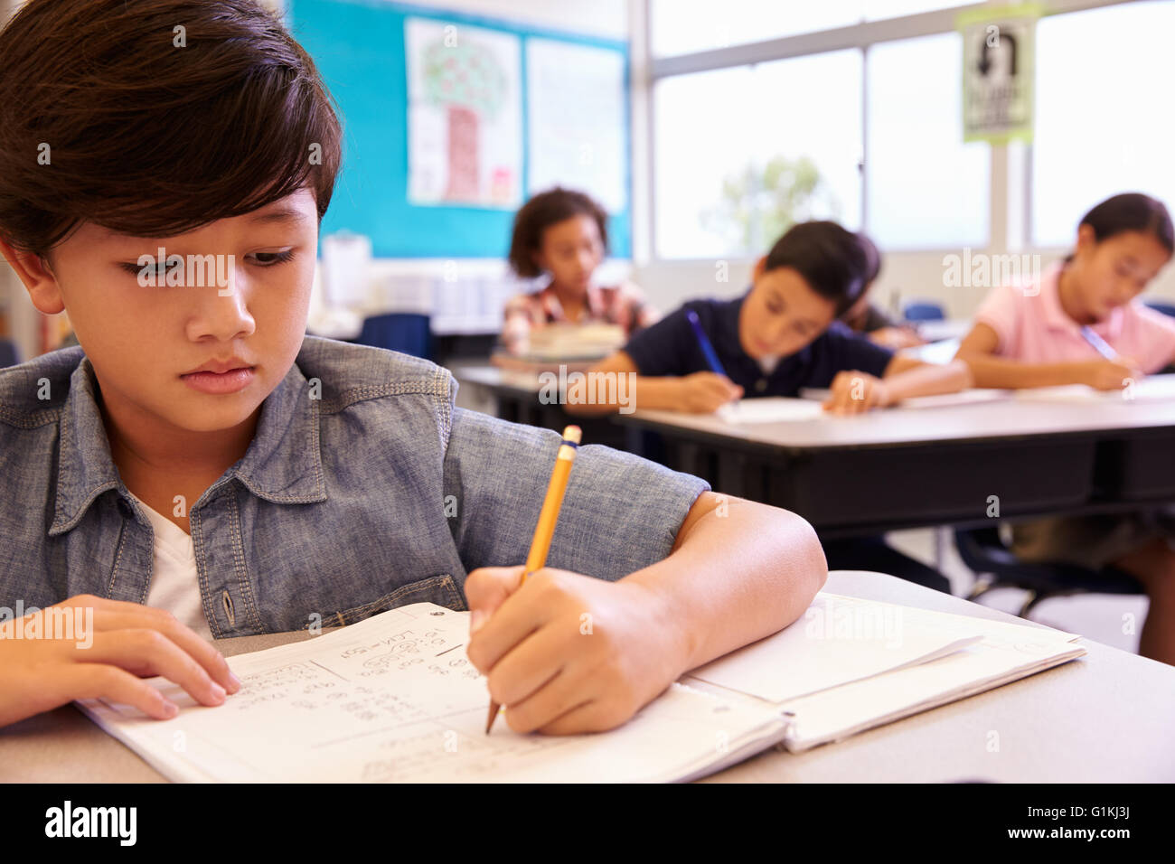 Asian schoolboy lavora nella scuola elementare di classe Foto Stock