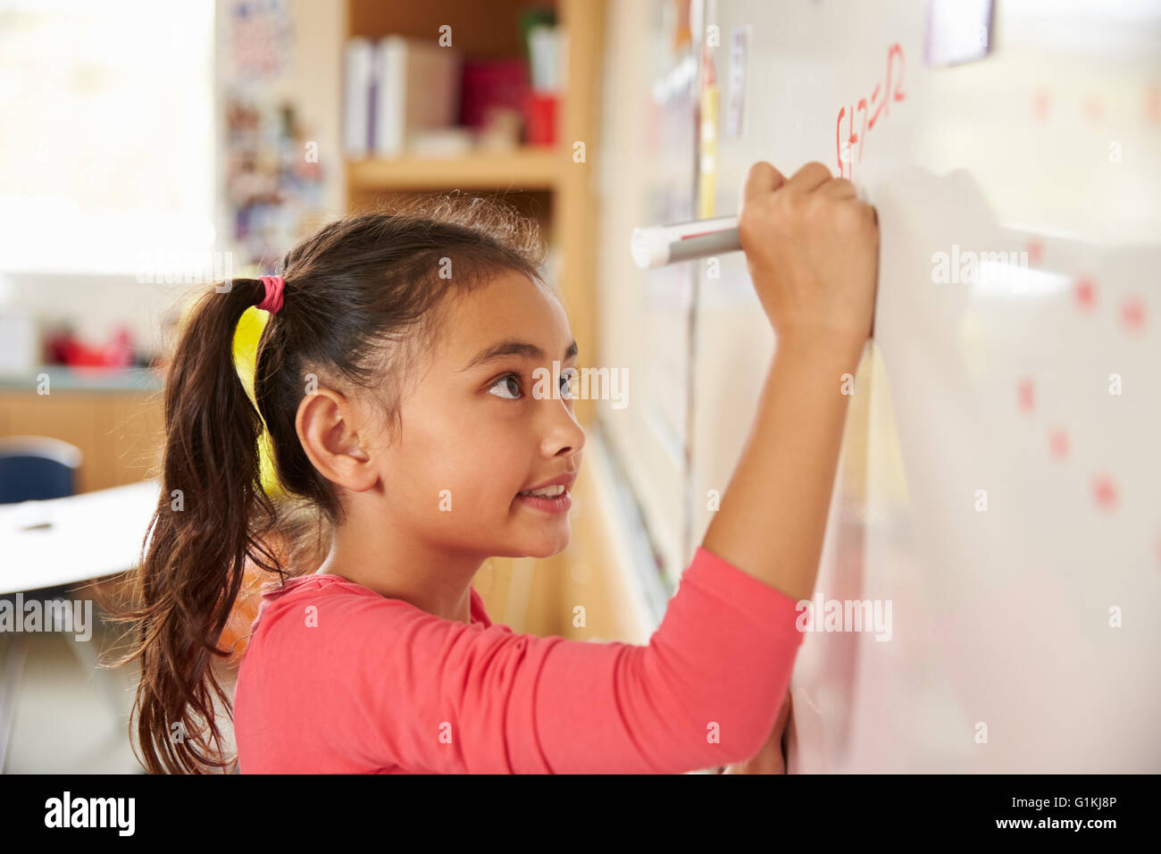 Pupillo la scrittura sulla scheda presso la scuola elementare di classe di matematica Foto Stock