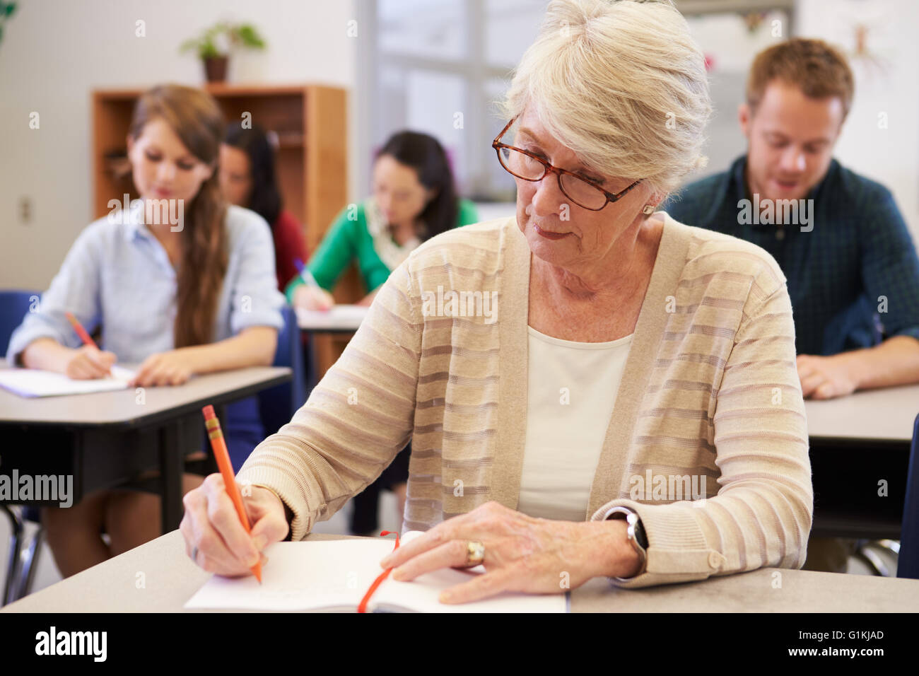 Senior donna a studiare in un'istruzione per adulti della classe Foto Stock